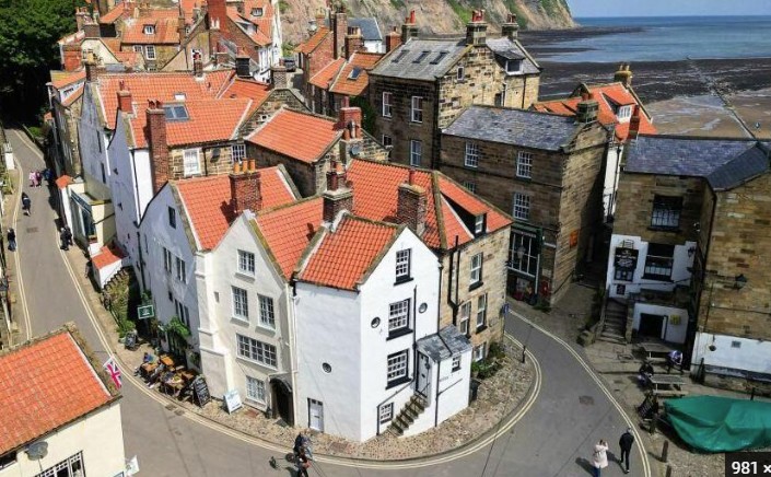 Red-roofed stone cottages and cobbled alleys tumbling down the ravine to the shore at Robin Hood's Bay