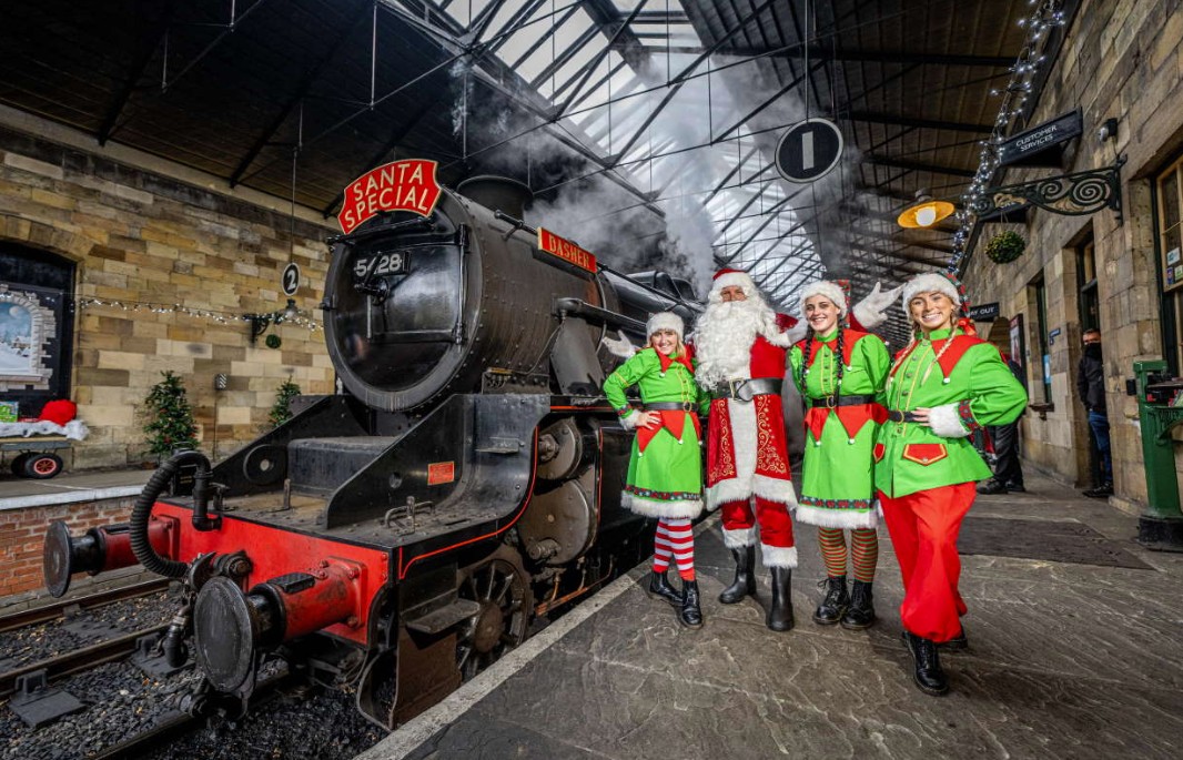 Santa and elves beside a decorated steam locomotive at the North Yorkshire Moors Railway Santa Special
