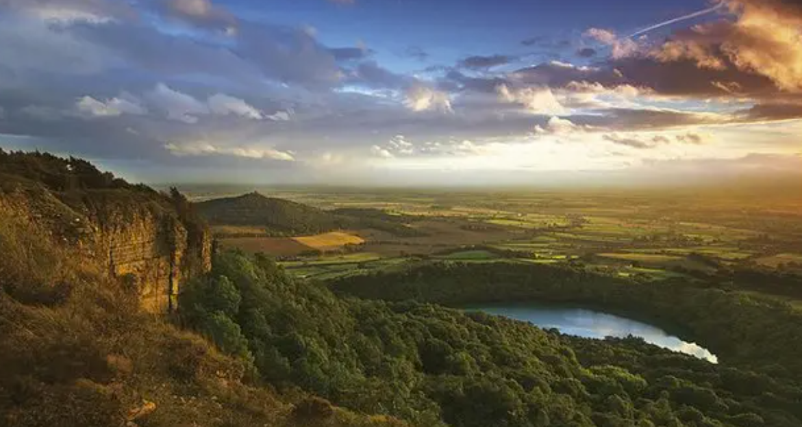 The Sutton Bank escarpment looking west over a patchwork of green farmland vales under a big sky