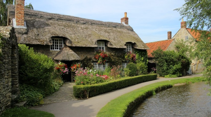 Flower-covered thatched cottage beside the beck at Thornton-le-Dale in the North York Moors