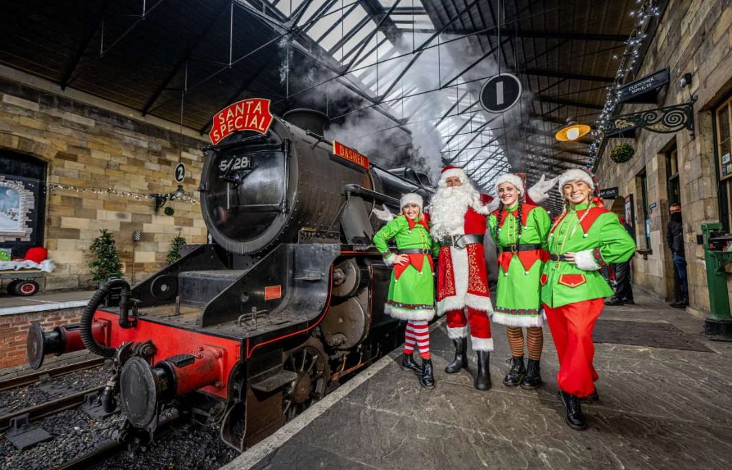 Santa and his elves beside a decorated steam locomotive at the North Yorkshire Moors Railway Santa Special