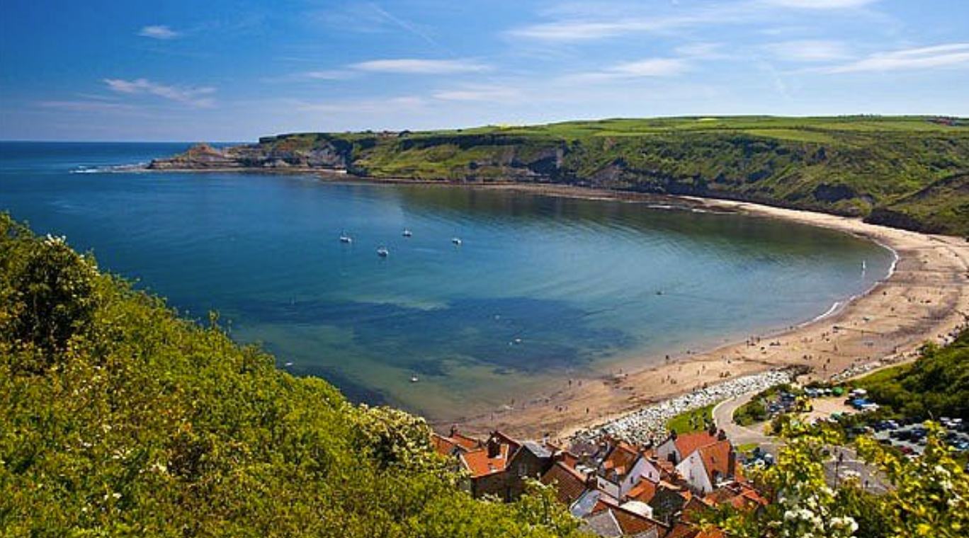 Runswick Bay beach curving around the sheltered blue bay below the clifftop