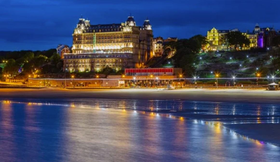 Scarborough South Bay at dusk, with the illuminated Grand Hotel reflected on the wet sand